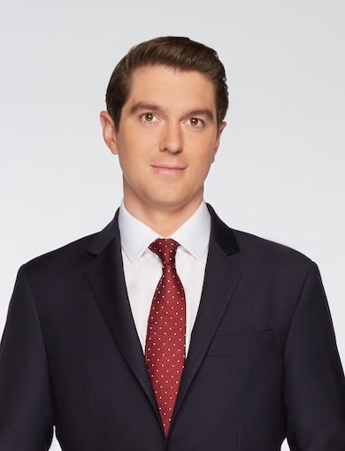 Caucasian male with brown hair and a black suit and red tie