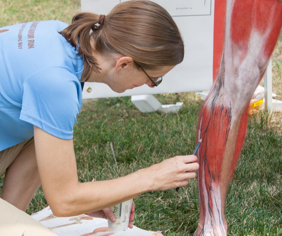 Elizabeth Weissbrod applying écorché painting on an athlete