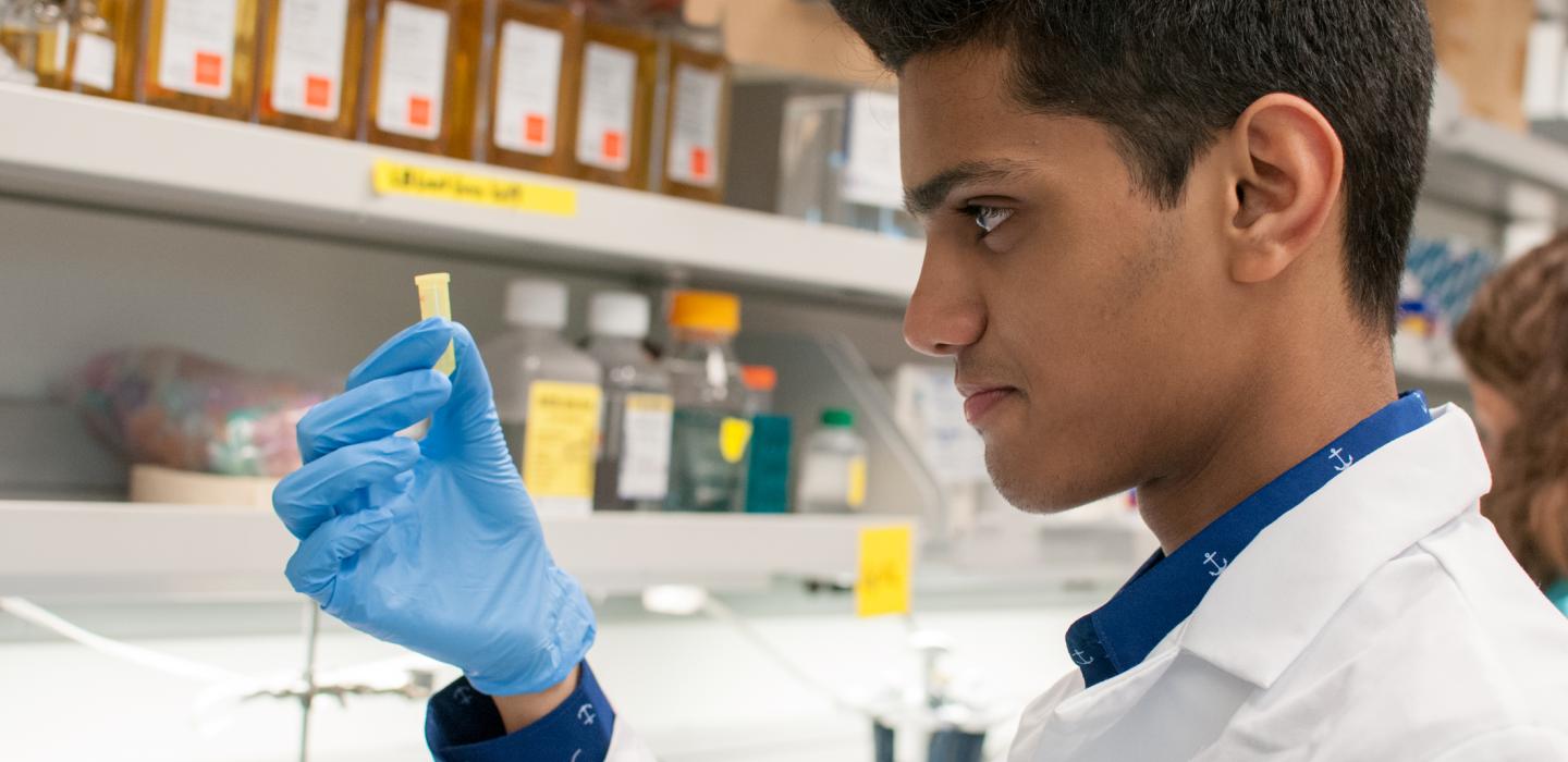 Male scientist looks at small beaker