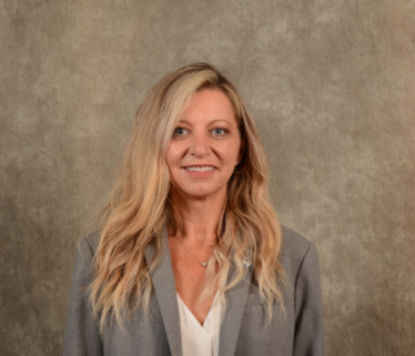 White woman executive with blond hair in grey suit against brown background