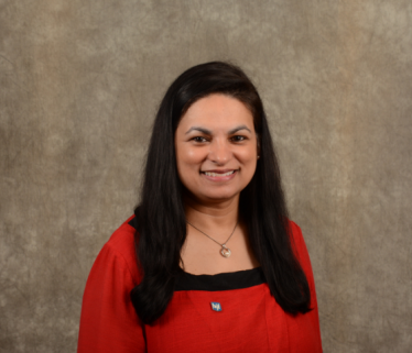 South Asian woman executive in red and black shirt with long black hair against brown background