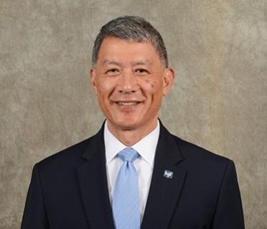 Asian American man in black suit with blue tie, Grayscale in the background