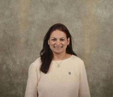 South Asian woman executive in red and black shirt with long black hair against brown background