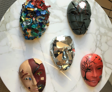 5 colorful masks arranged in a two-one-two pattern on a white table