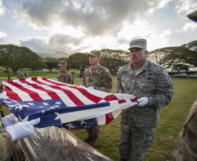 Soldiers hold American flag over casket