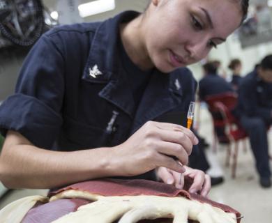 Navy corpsman preforms a needle decompression on a simulated cadaver