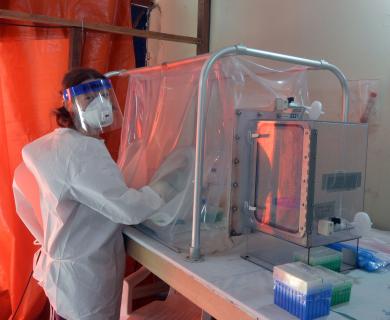 Female scientist in full gown and working in a containment box