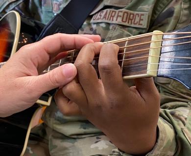 person helping someone with a guitar