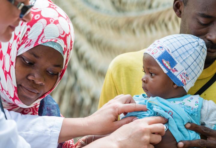 Medical doctor works with three people, two children one adult