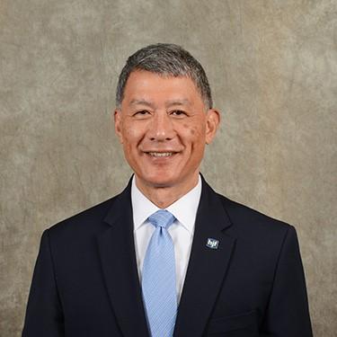 Asian American man in black suit with blue tie, Grayscale in the background