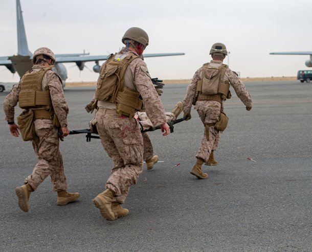 Four military men carry someone on a stretcher at an Air Force Base