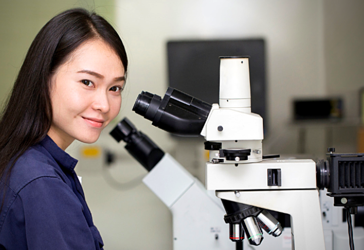 Researcher at microscope looking out