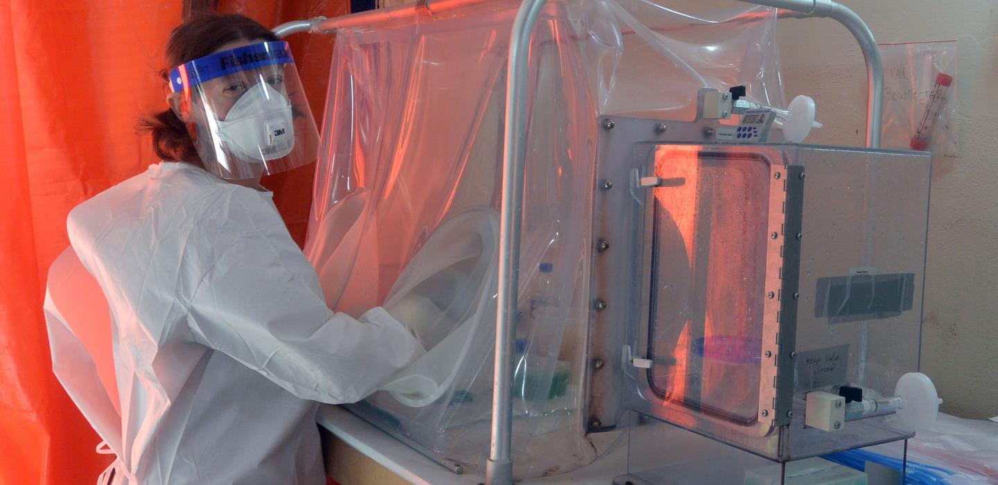 Female scientist in full gown and working in a containment box